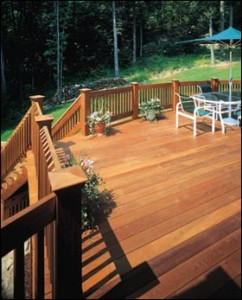 Photo of a large unpainted wooden outdoor patio with an unpainted wooden picket fence.